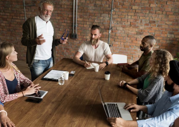 A team meeting around a wooden table with laptops and tablets